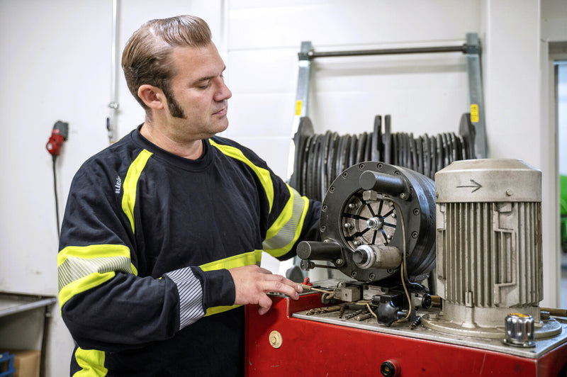 Håkan pressar en hydraulslang.